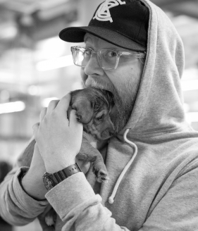 Black and white photo of Ryan Kopperud, devouring a small puppy