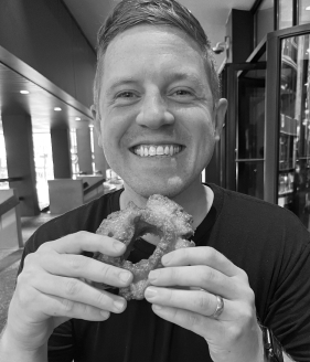 Black and white photo of Ty Thorsen, euphorically preparing to eat a doughnut